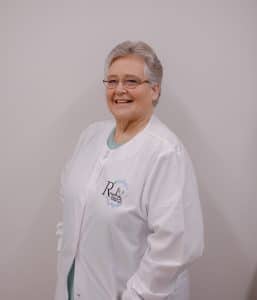 Smiling person in a white lab coat.