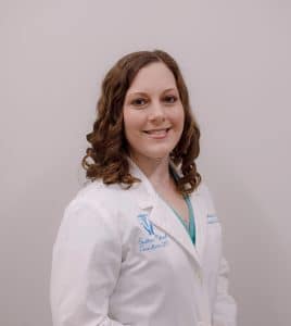 Smiling woman in white medical coat.