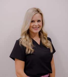 Woman smiling in black scrub top.
