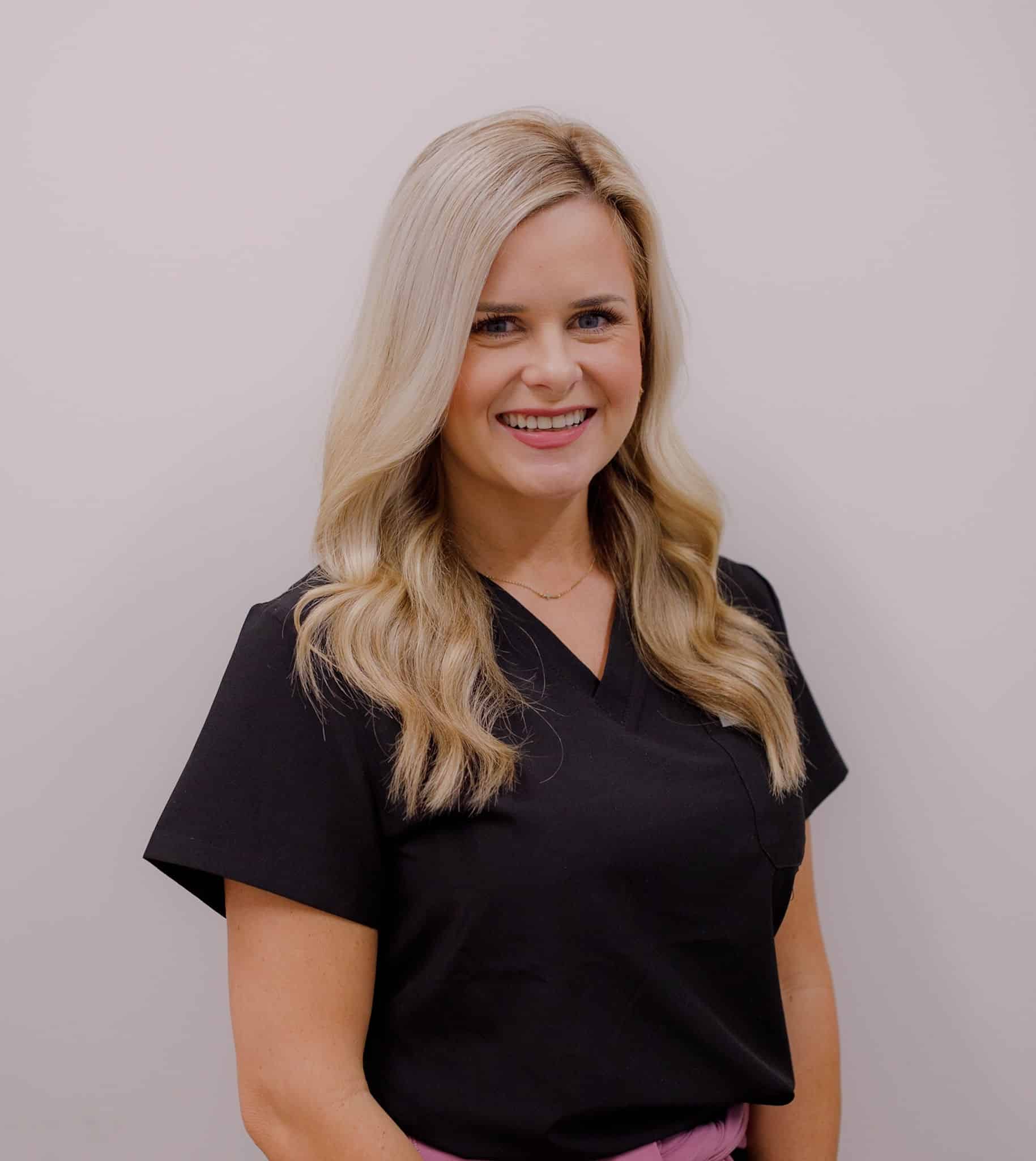 Woman smiling in black scrub top.